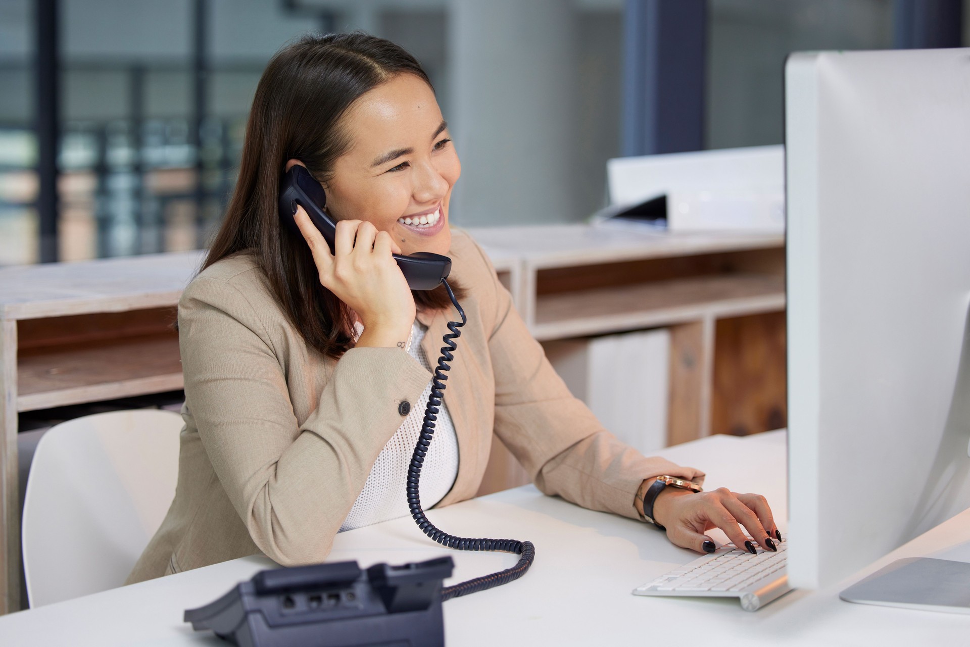 Shot of a young woman using a telephone and computer in a modern office
